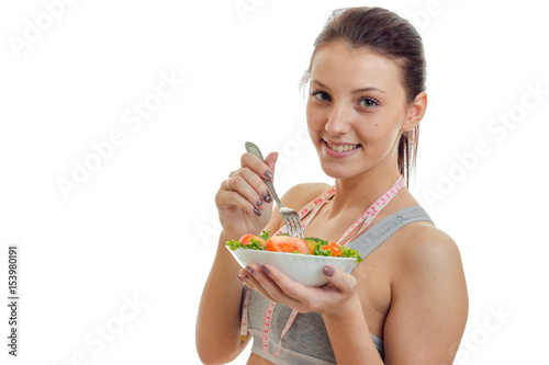 young beautiful smiling girl holding near the face plate of a vegetable salad closeup