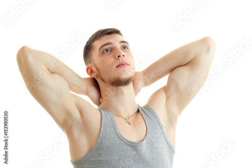 young strong guy with the session you muscles raised hands behind the neck and looking up isolated on a white background