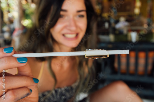 straw with ice in the girl's hand, against the background of her smile. photo