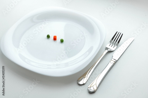 Diet dish from three peaces of vegetables on the white dish with fork and knife