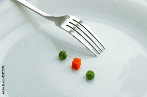 Diet dish on the white plate with fork. Thre peaces of vegetables
