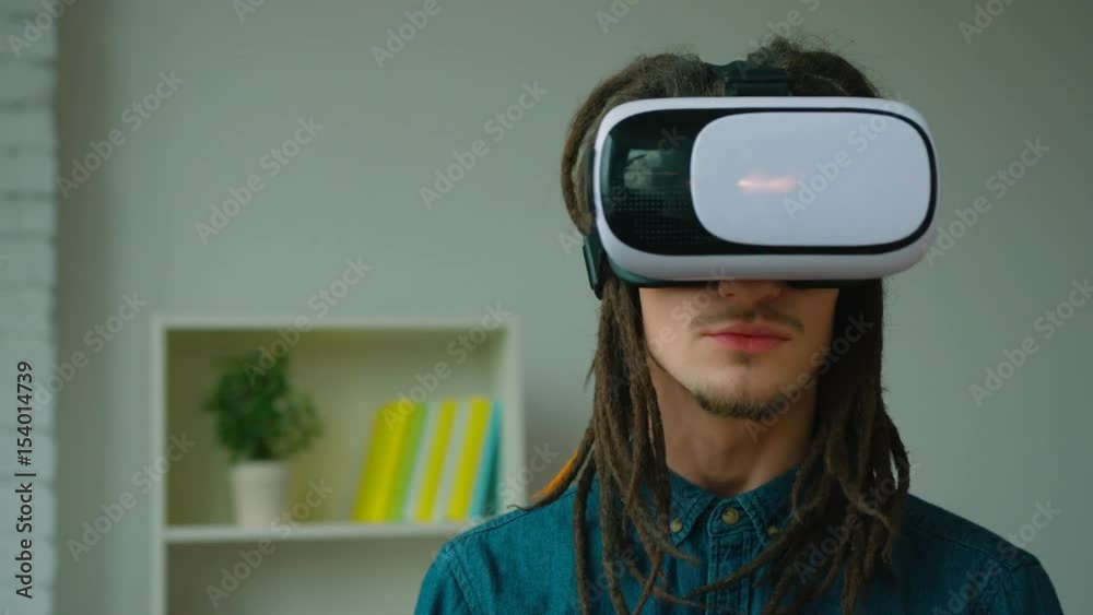 Young hipster man with dreadlocks using virtual reality headset at home. Vr glasses. Young hipster man with dreadlocks using virtual reality headset at home. Vr glasses.