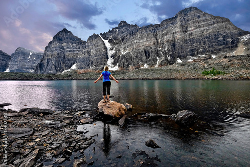 Meditation by lake in Valley of Ten Peaks.  Inner peace. Young woman meditating. Banff National Park. Eiffel lake. Wenkchemna Pass. Canadian Rocky Mountains.   Alberta. Canada. photo