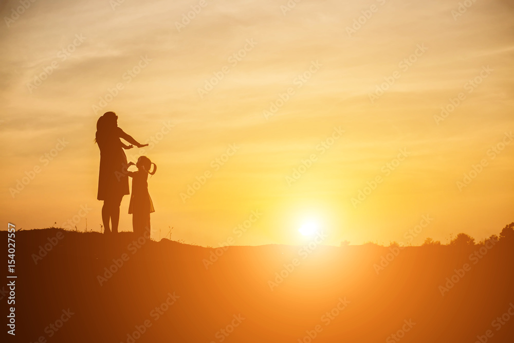 Mother encouraged her daughter out of the shadows at sunset.