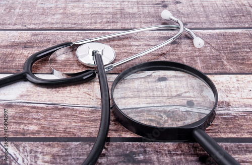 Stethoscope With Magnifying Glass On Wooden Background.
