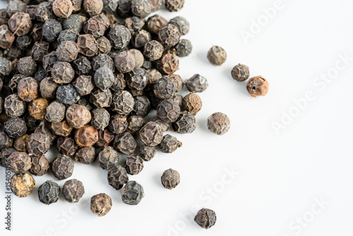 Black pepper seeds on a white background with some blurry effects (bokeh) applied. Organic seeds origin from Sarawak of Borneo, Malaysia.