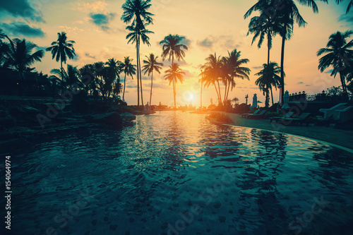 Tropical beach with silhouetted palm trees during sunset.