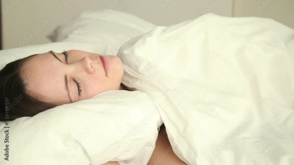 Young beautiful female having sleep problems, moving restless on bed, unable to fall asleep, having nightmare, lying with her eyes closed on uncomfortable mattress, can't find comfortable position Young beautiful female having sleep problems, moving restless on bed, unable to fall asleep, having nightmare, lying with her eyes closed on uncomfortable mattress, can't find comfortable position