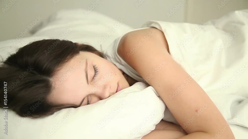 Young beautiful female having sleep troubles, moving restless on bed, unable to fall asleep, having bad dream, lying with her eyes closed on uncomfortable mattress, can not find comfortable pose Young beautiful female having sleep troubles, moving restless on bed, unable to fall asleep, having bad dream, lying with her eyes closed on uncomfortable mattress, can not find comfortable pose