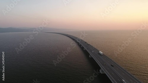 Endless road low-water bridge over Amursky gulf De-friz and Sedanka Vladivostok, Russia. Constructed for APEC summit. Modern architecture. Helicopter flight follow cars aerial. Sunset photo