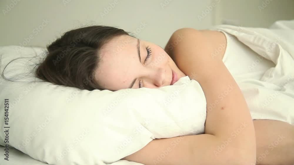 Young beautiful happy adult lady sleeping soundly on bed in bedroom at home or hotel, hugging white comfy pillow, having good dream, lying with her eyes closed on comfortable mattress in relaxed pose Young beautiful happy adult lady sleeping soundly on bed in bedroom at home or hotel, hugging white comfy pillow, having good dream, lying with her eyes closed on comfortable mattress in relaxed pose