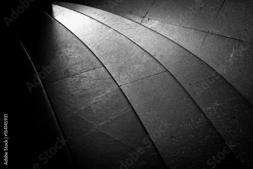 Granite stairs in black and white. Curved with light shining on them.