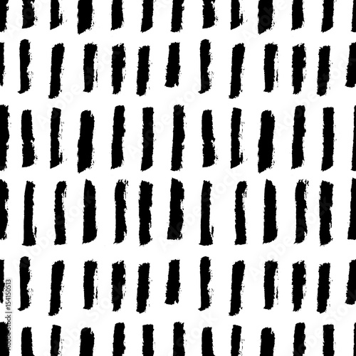 Abstract monochrome seamless pattern with ink black vertical hand drawn brushes. Grunge lines, or stripes isolated on white background. Minimalistic naive scandinavian design. Vector illustration.