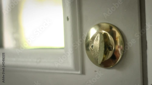 Multipurpose clip - Man locks and unlocks his double gold deadbolt lock on modern door photo