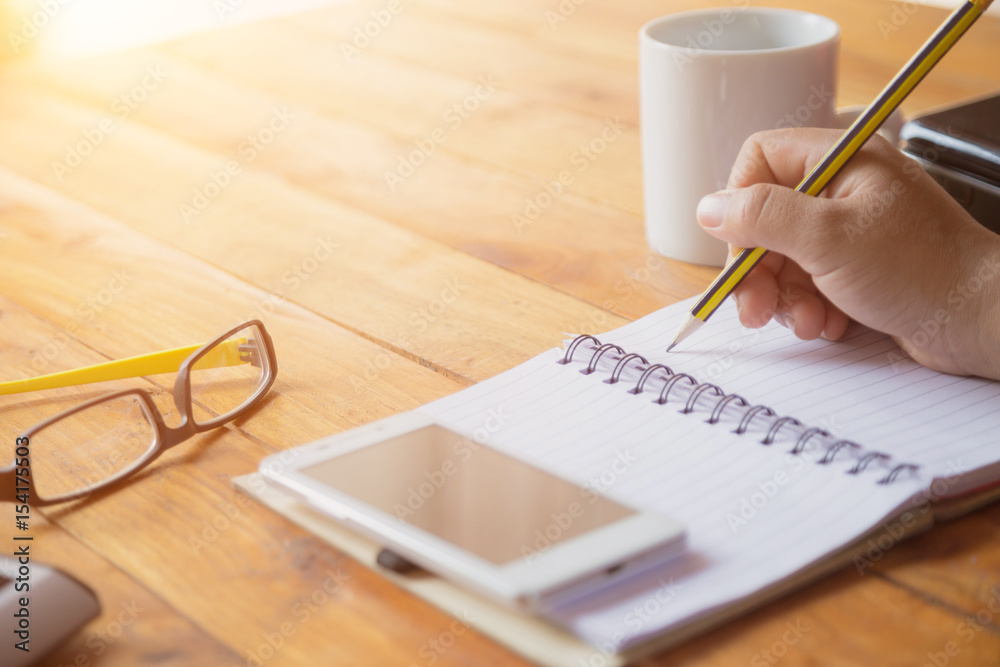 Closeup of a female hand writing on an blank notebook with a pen. Closeup of a female hand writing on an blank notebook with a pen.