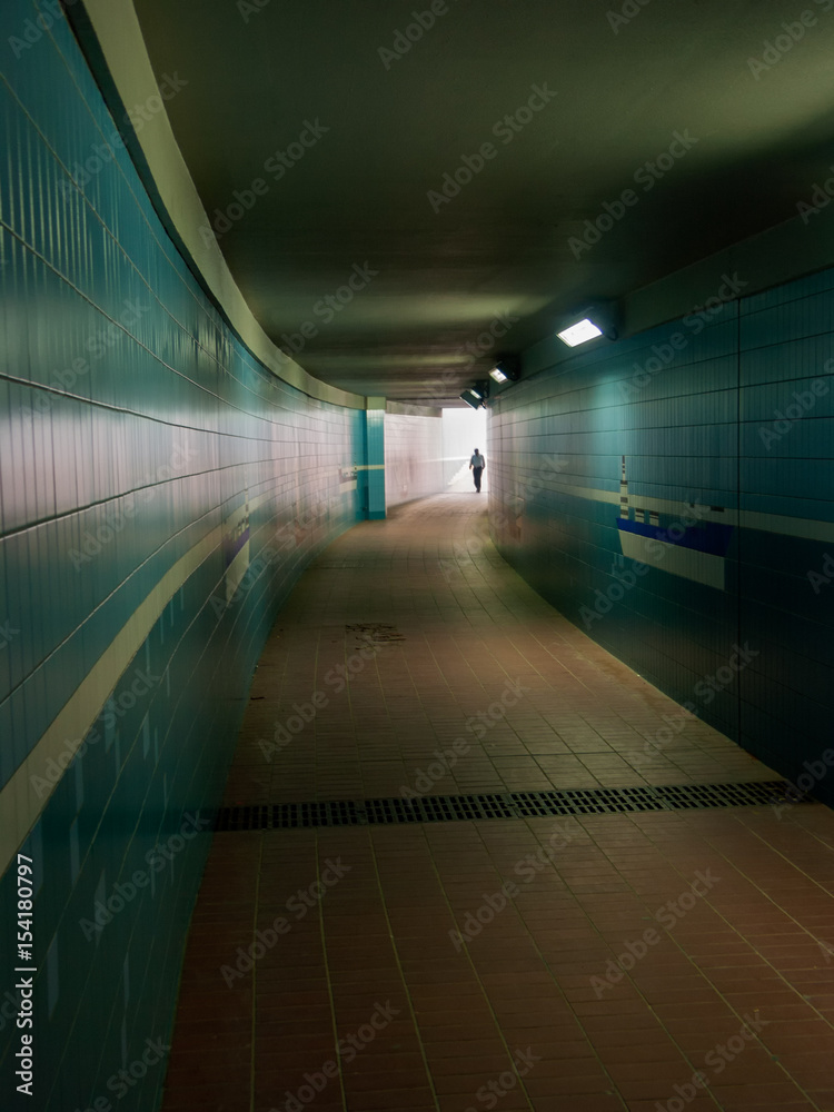 male entering a lit tunnel or underground passage