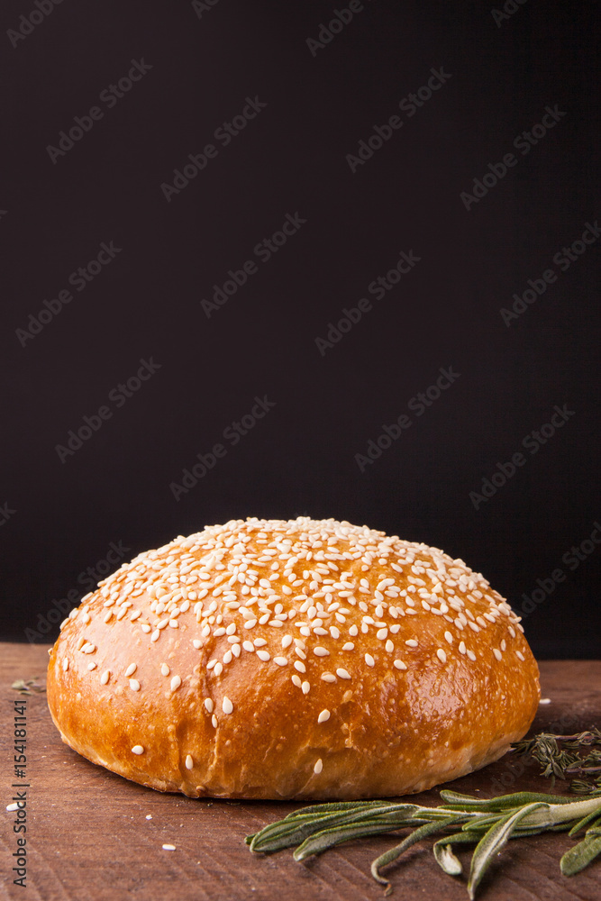 Close-up of burger bun with sesame seeds on black background