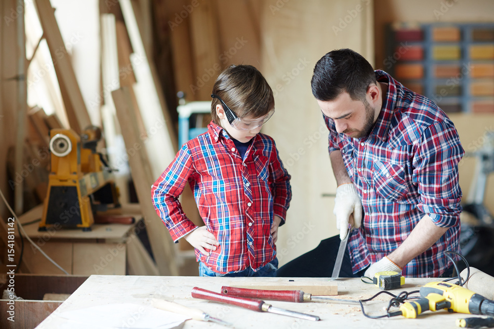 Little boy and his father wood-carving in workshop Little boy and his father wood-carving in workshop