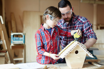 Boy measuring length of starling-house roof