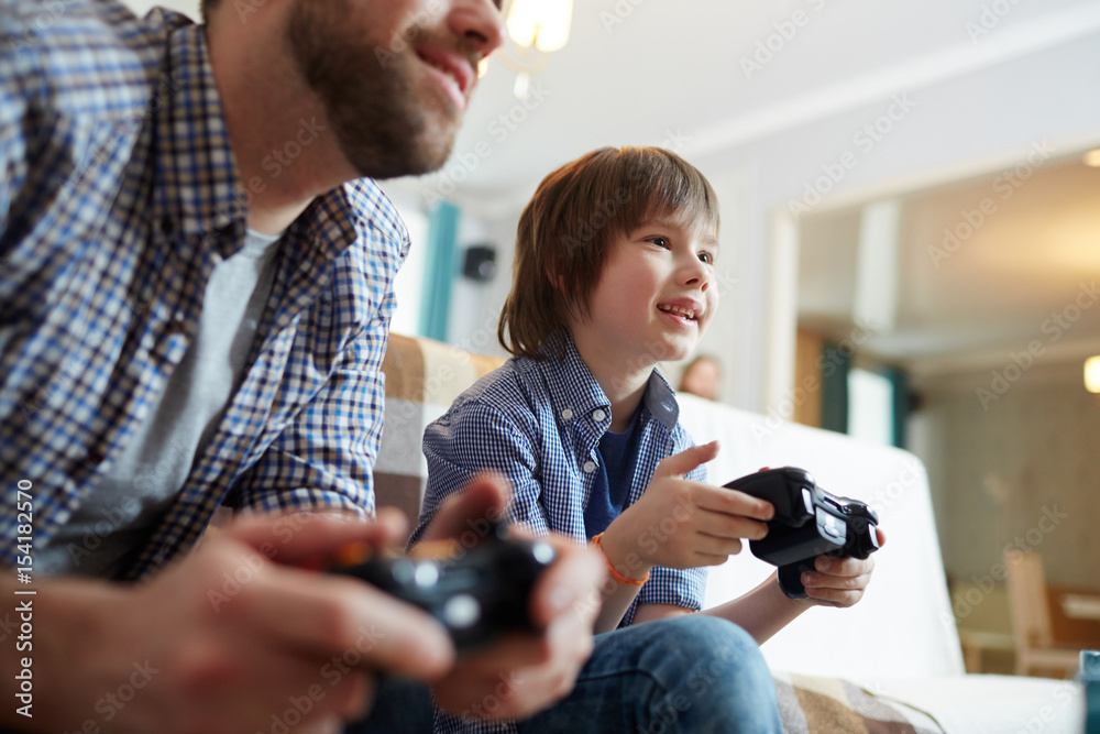 Happy boy with console and his father playing video game at home Happy boy with console and his father playing video game at home