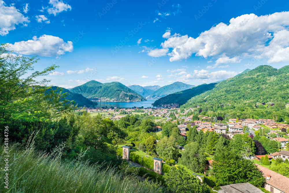Lake Lugano, Porto Ceresio and Besano (Valceresio), Italy. Picturesque aerial view, in the background the Switzerland with Morcote, Melide, the Alps on a beautiful day with blue sky and white clouds