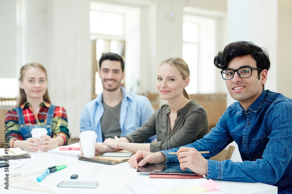 Creative designers sitting by desk and looking at camera Creative designers sitting by desk and looking at camera