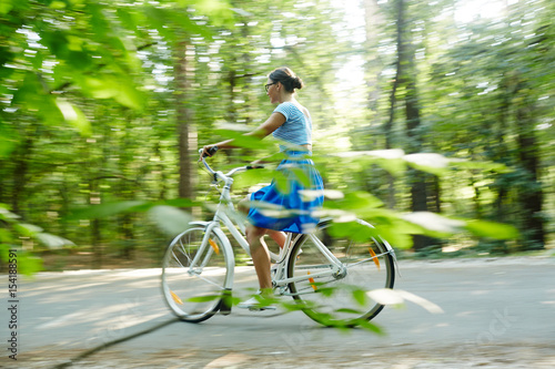 Modern girl riding bicycle down country road