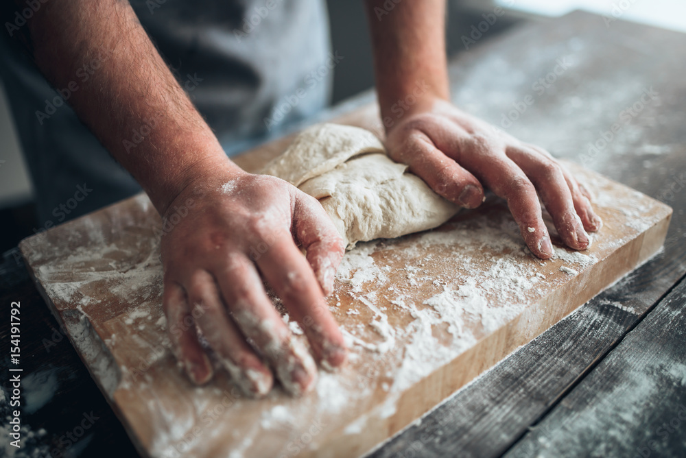 Baker hands kneading the dough with flour Baker hands kneading the dough with flour