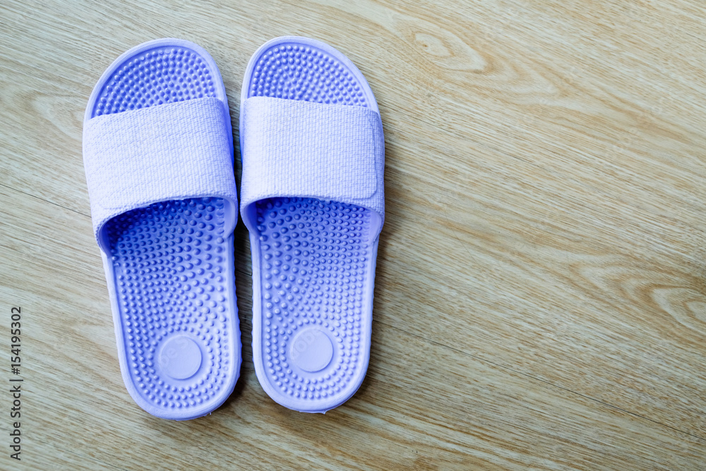 A pair of healthy blue rubber slippers on wooden floor A pair of healthy blue rubber slippers on wooden floor