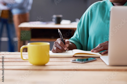 African businesswoman writing notes at her desk in an office
