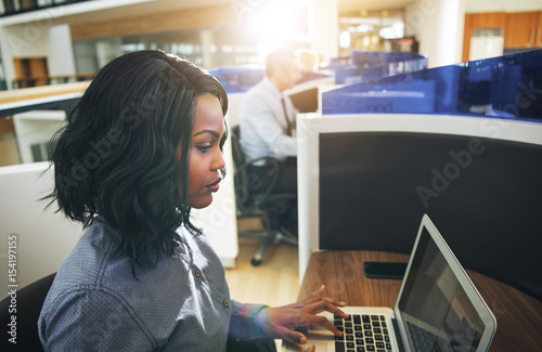 Young black woman typing laptop at workplace in office
