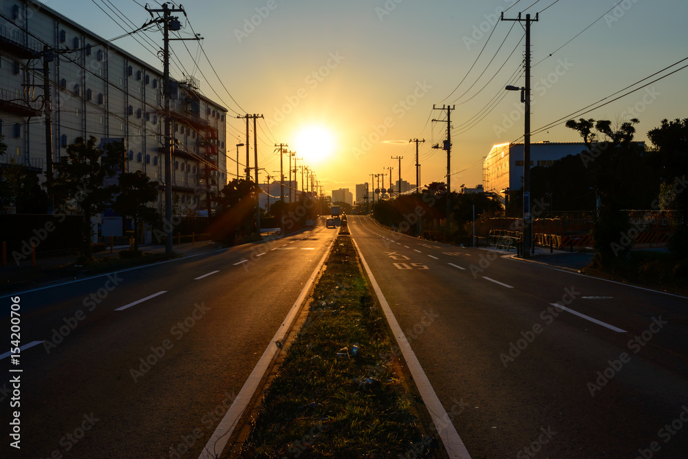 夕日に向かって真っ直ぐ伸びる日本の道路