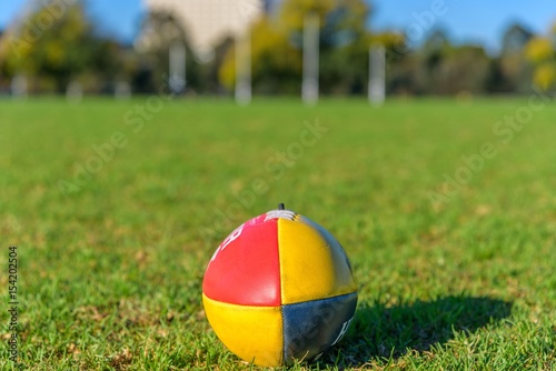 фотографія A single close football on a field with a set of Australian Football League goal posts in the background in Melbourne Australia