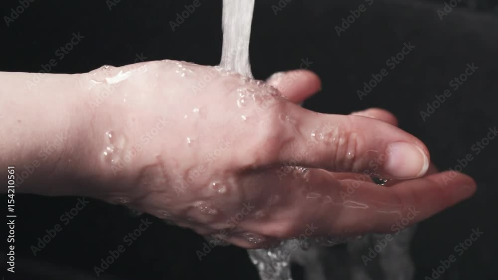 Slow motion handheld shot of girl holding hand under water stream from faucet, 180fps prores footage Slow motion handheld shot of girl holding hand under water stream from faucet, 180fps prores footage