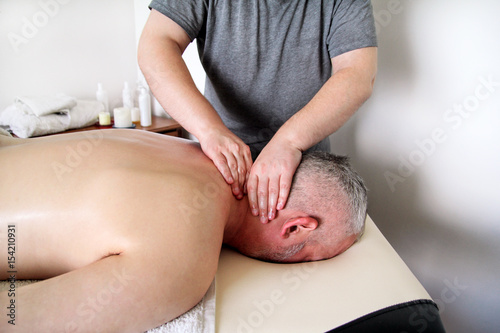 Sports massage studio. Massage therapist massaging shoulders of a male athlete  working with neck muscles. Body care. Man having massage in the massage salon. Massage neck muscles. Massage table.