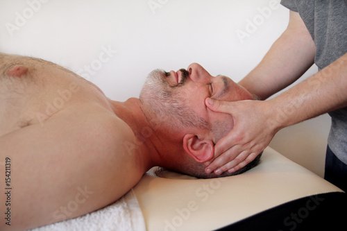 Massage studio. Men hands masseuse for massage the head of a guy. Body care. Man having massage in the spa body massage salon. Massage table.