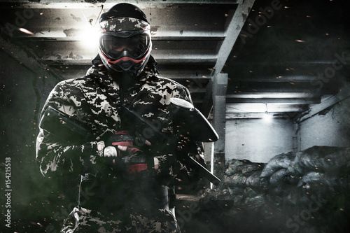 Heavily armed masked paintball soldier on post apocalyptic background. Ad concept.