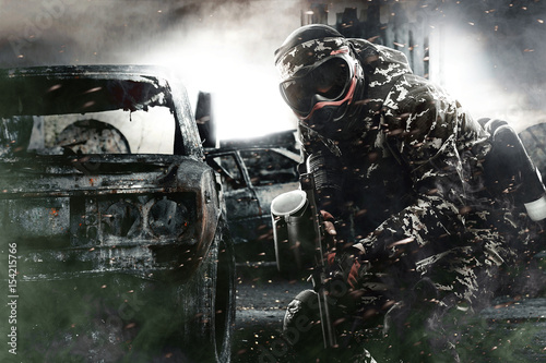 Heavily armed masked paintball soldier on post apocalyptic background. Ad concept.