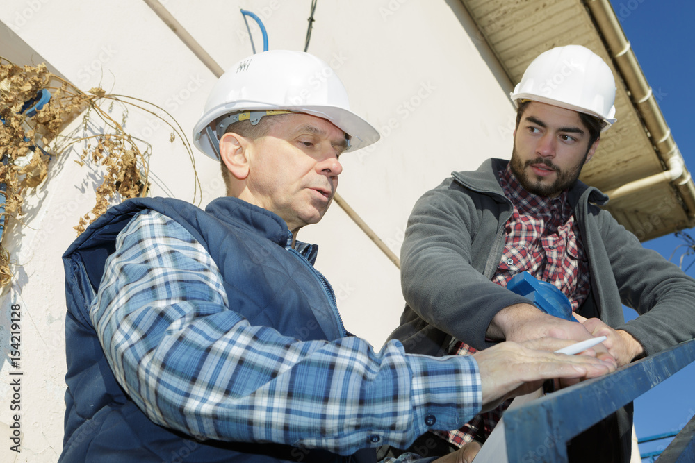 manual worker with clipboard showing something to co-worker manual worker with clipboard showing something to co-worker