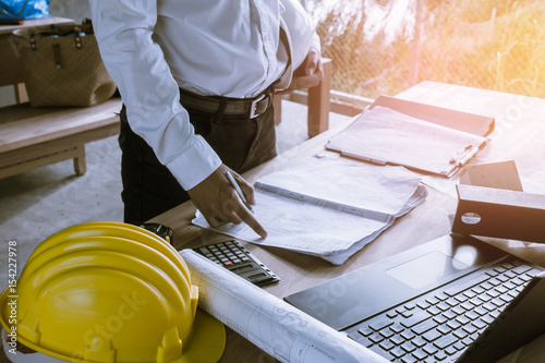 Engineer concept : Architect working on blueprint.engineer inspective in workplace , laptop ,calculator, blueprints,helmet. Vintage filter effect photo