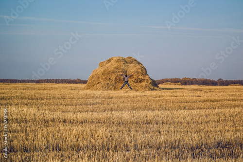 Happy man and hay stack in the wheat field.