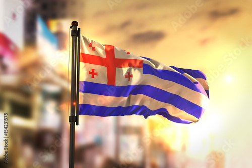 Adjara Flag Against City Blurred Background At Sunrise Backlight photo