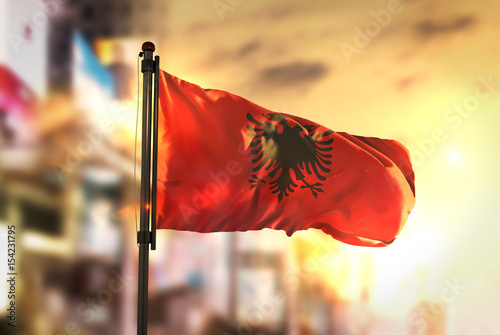 Albania Flag Against City Blurred Background At Sunrise Backlight