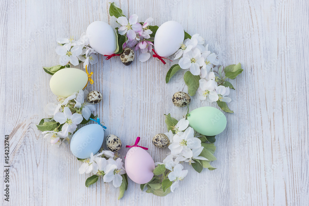 round of easter pastel painted eggs and quail eggs on light wooden background