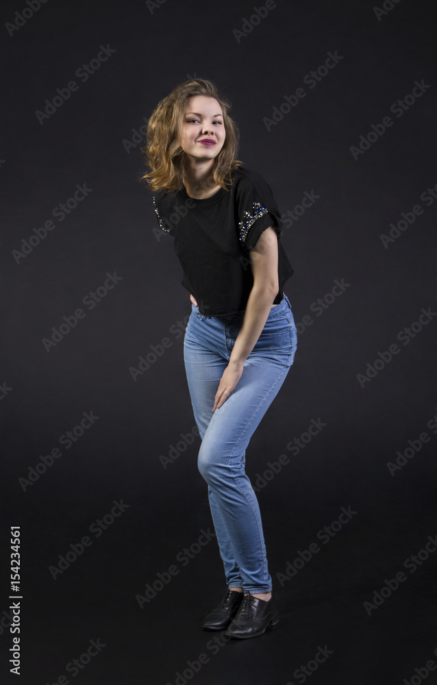 A young,smiling girl in jeans and short t-shirt posing in the Studio. Studio photography on an even background,isolated image.