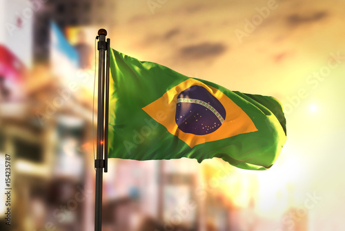 Brazil Flag Against City Blurred Background At Sunrise Backlight