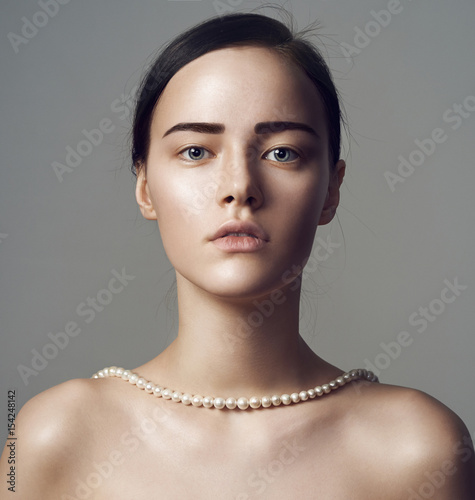 Portrait of beautiful sensual woman with holding in pearl jewelry.
