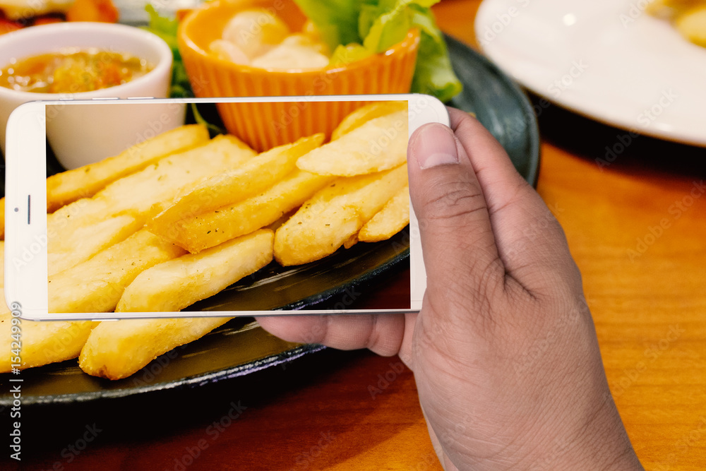 hand holding smartphone with french fries on screen with blurred background hand holding smartphone with french fries on screen with blurred background
