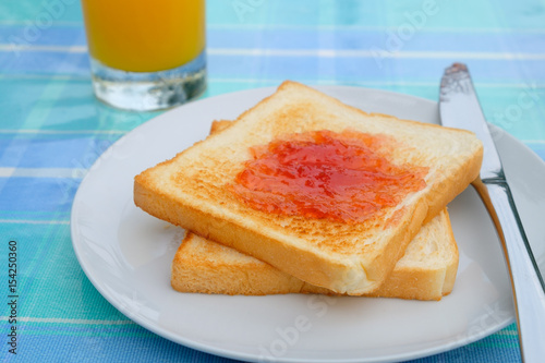 side view close up strawberry jam on double bread put on white plate.