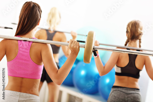 Group of smiling people lifting barbells